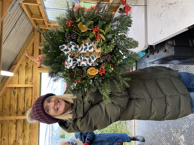 Picture of smiling lady holding up a Christmas wreath